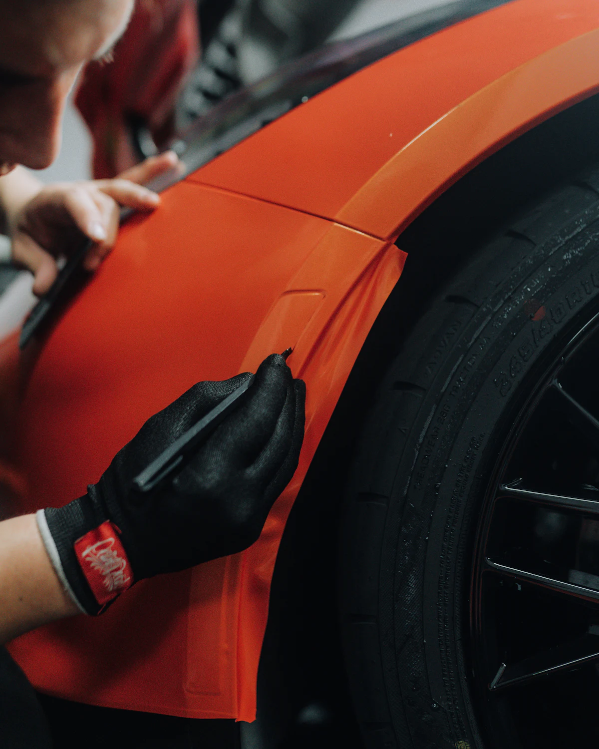 Installer trimming orange film around a rear wheel arch