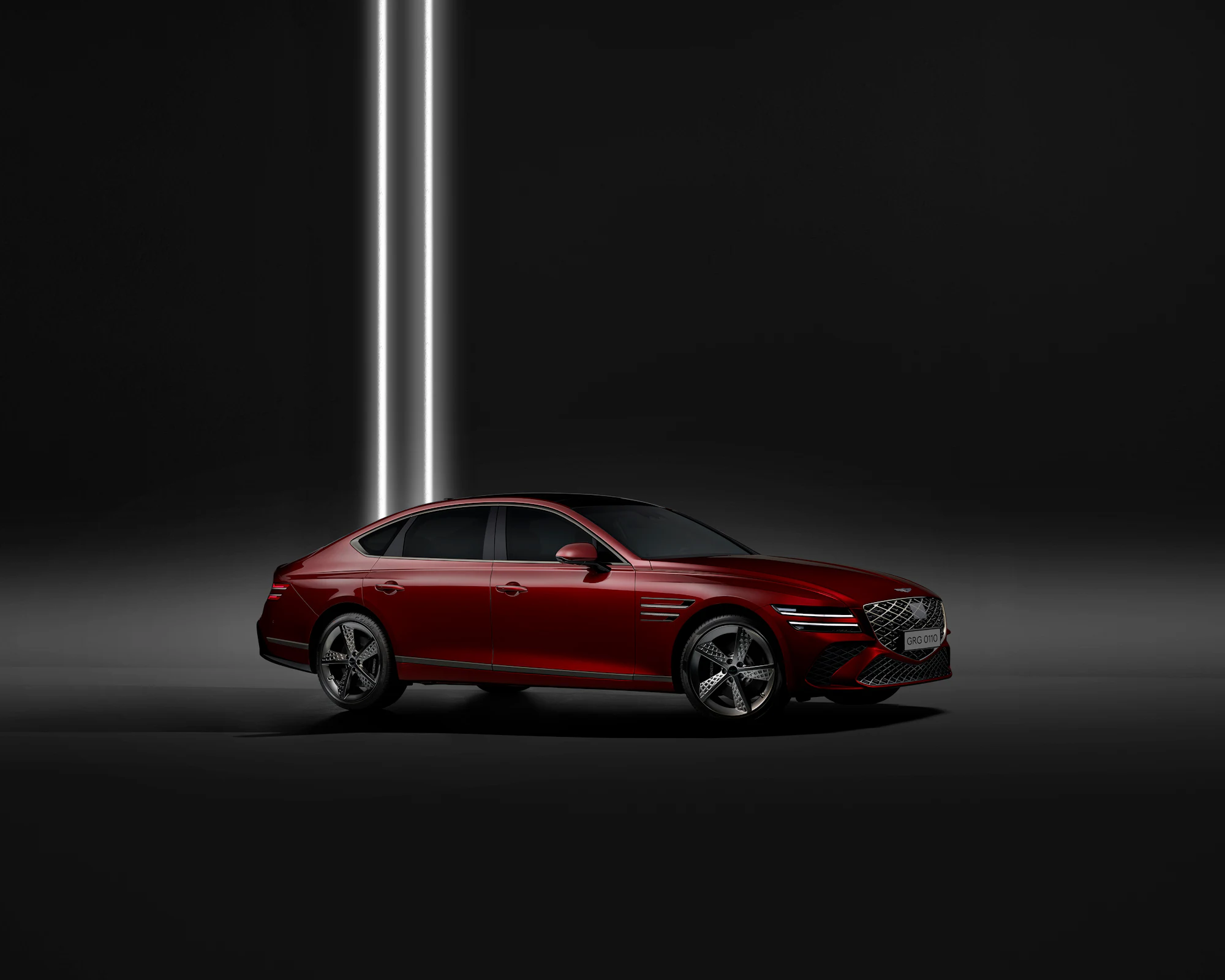 Red sedan in a black studio under a single vertical strip light
