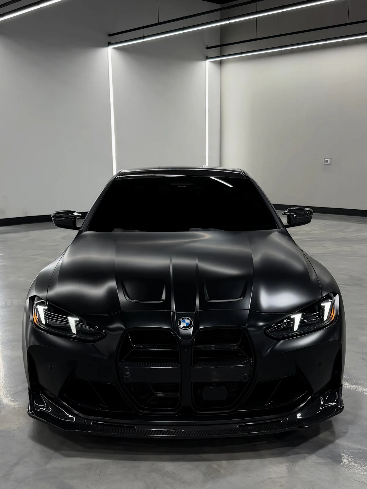 Satin black coupe in a white studio with strip lighting